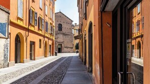 A narrow street with buildings on either side, a cobblestone path, and a large building in the background. - Suite Modena al Centro - Affitti Brevi Italia (Modena)