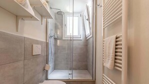 A modern bathroom with a glass-enclosed shower, a toilet, and a towel rack. - Suite Modena al Centro - Affitti Brevi Italia (Modena)