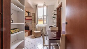 A room with a dining table, chairs, a radiator, and a window with curtains. - MonoliVi 35 - Affitti Brevi Italia (Modena)