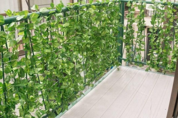 Un balcone con ringhiera in metallo verde e pavimento in legno.
