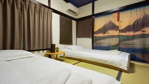 A traditional Japanese-style room with tatami flooring, two single beds, a small table, and a wall painting of a mountain landscape. - Takinoen Standalone House for 7 12 mins Train to Ueno (Tokyo)