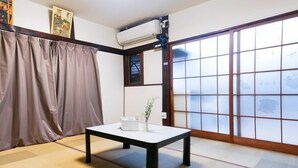 A traditional Japanese room with tatami flooring, a low table with a white tray, and a sliding glass door with a view. - Takinoen Standalone House for 7 12 mins Train to Ueno (Tokyo)