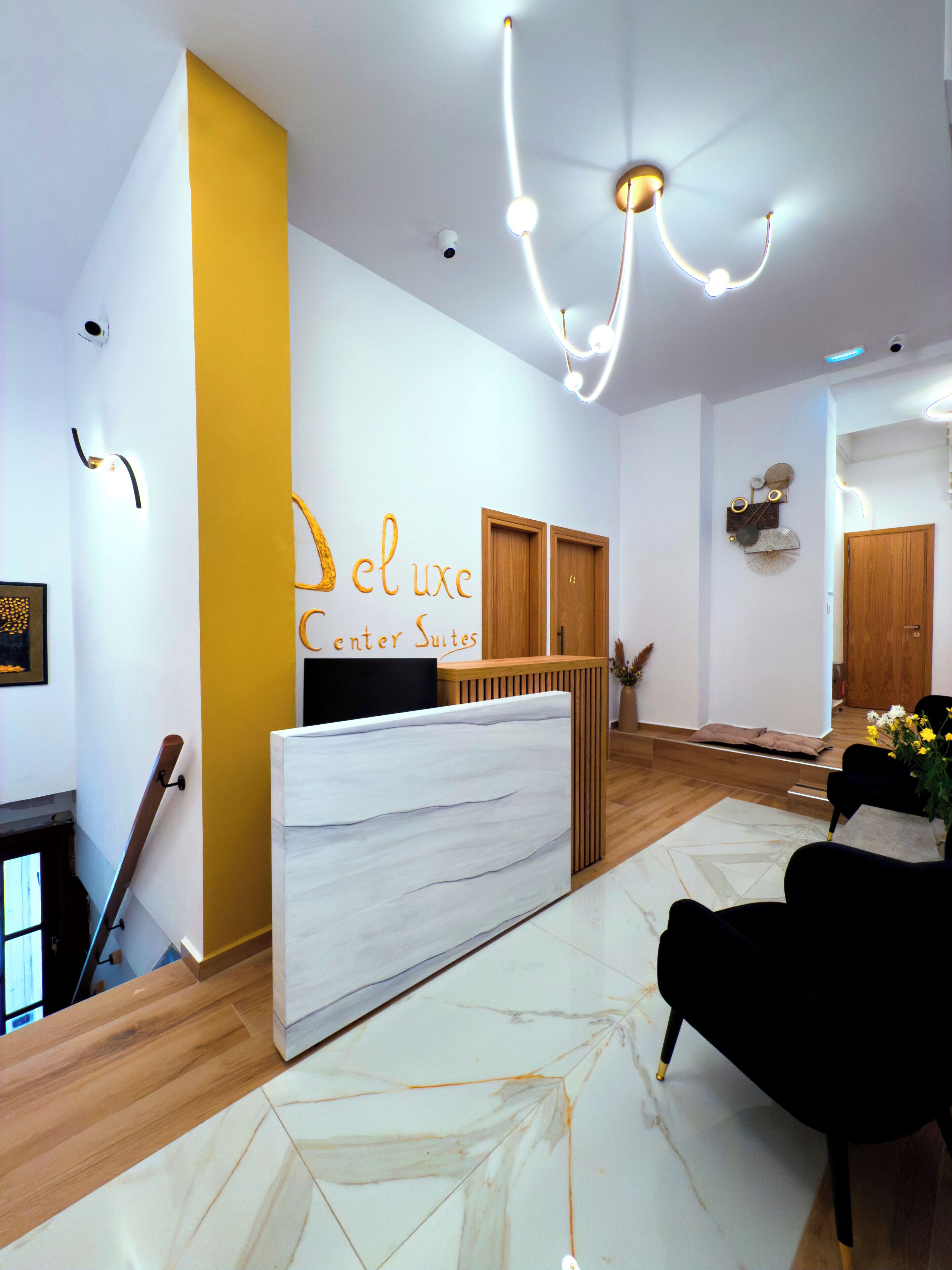 A reception area with a marble reception desk, wooden flooring, and a modern chandelier.