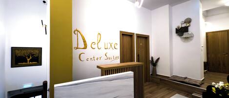 Zona de recepción de hotel con diseño moderno, que incluye un mostrador, un cartel en la pared y una puerta de madera.