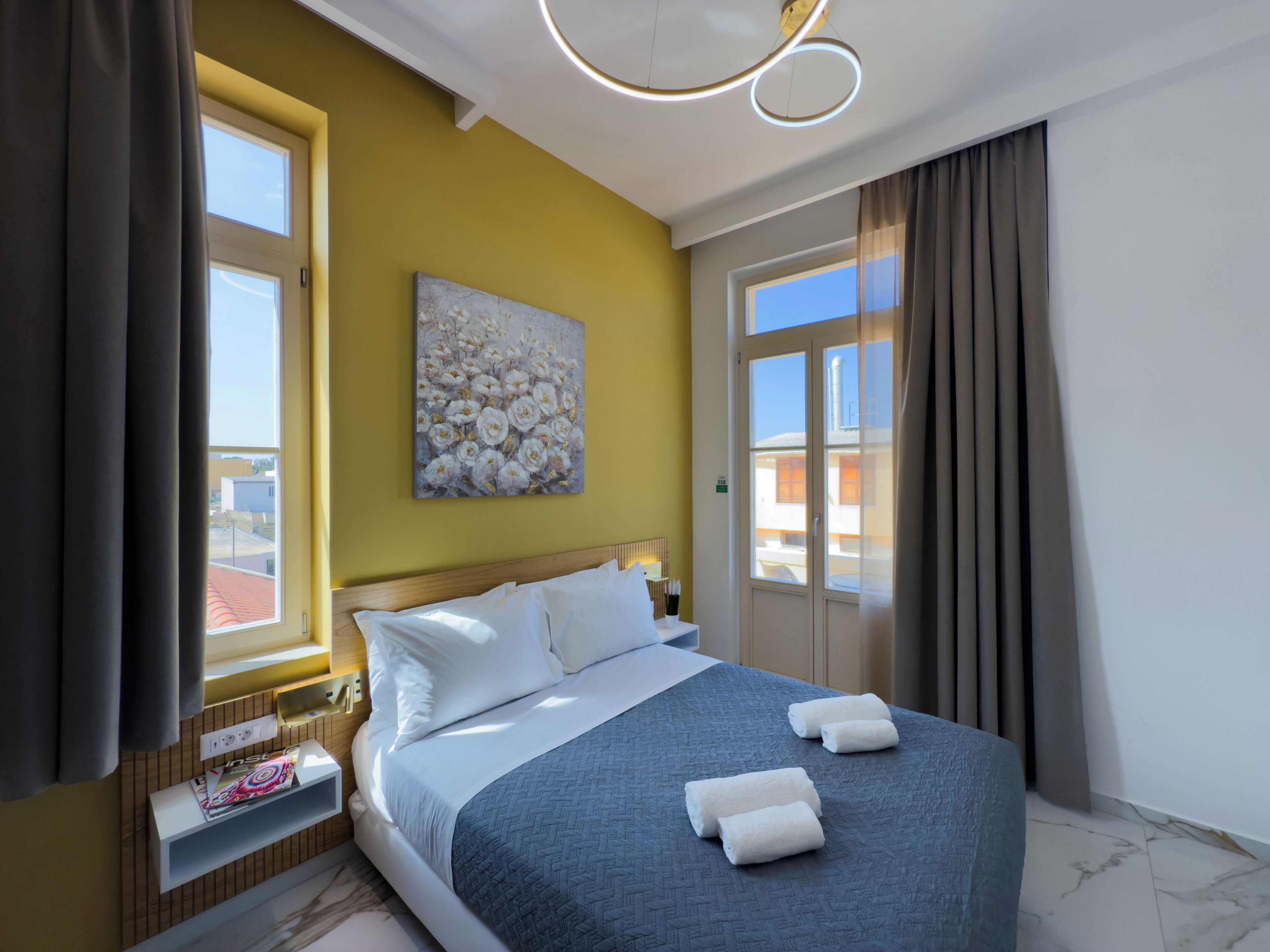 Ein Hotelzimmer mit einem Bett, einem Gemälde, einem Fenster und Blick auf Gebäude.