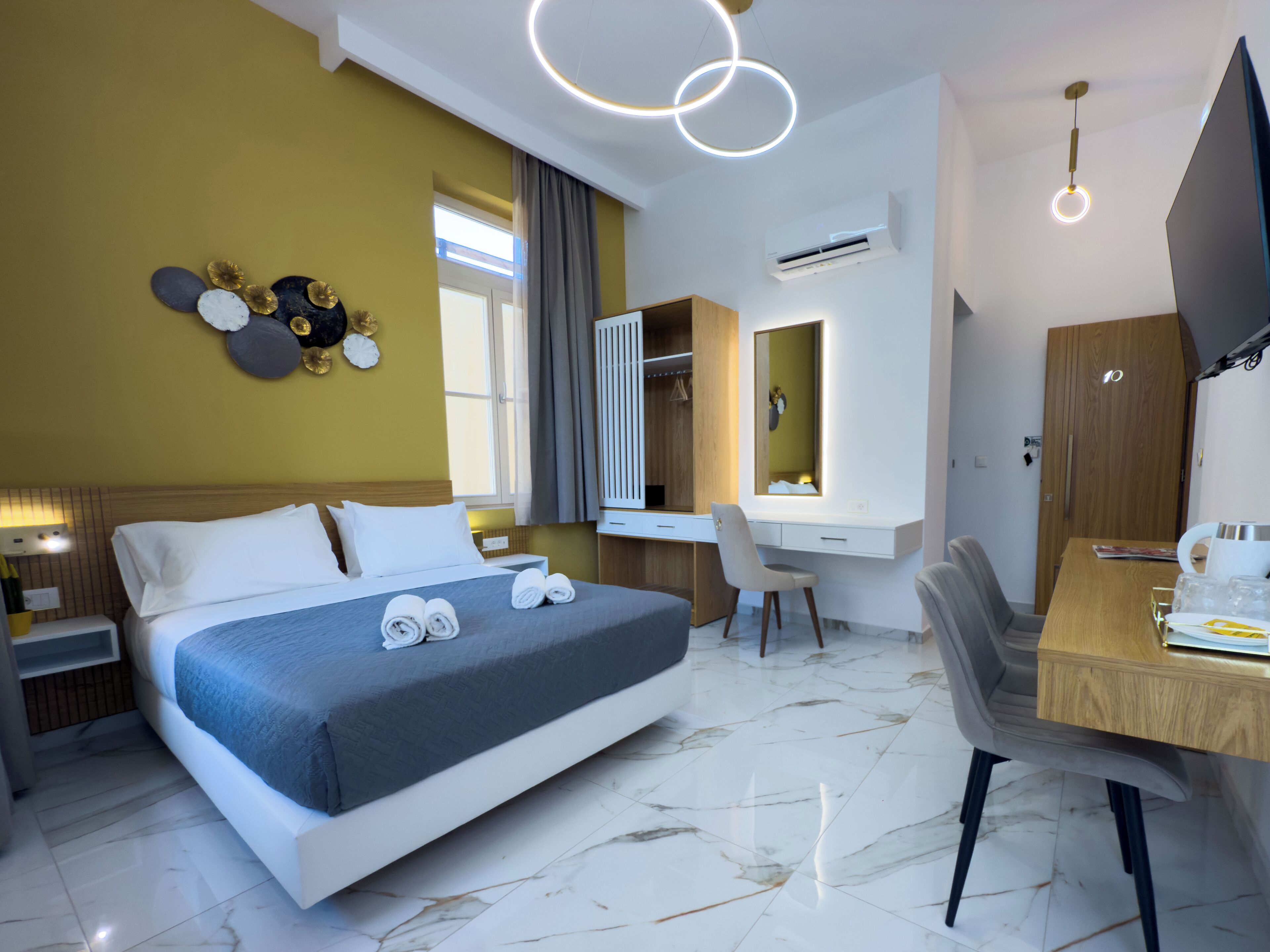 A modern hotel room with a large bed, a desk, a chair, and a TV.
