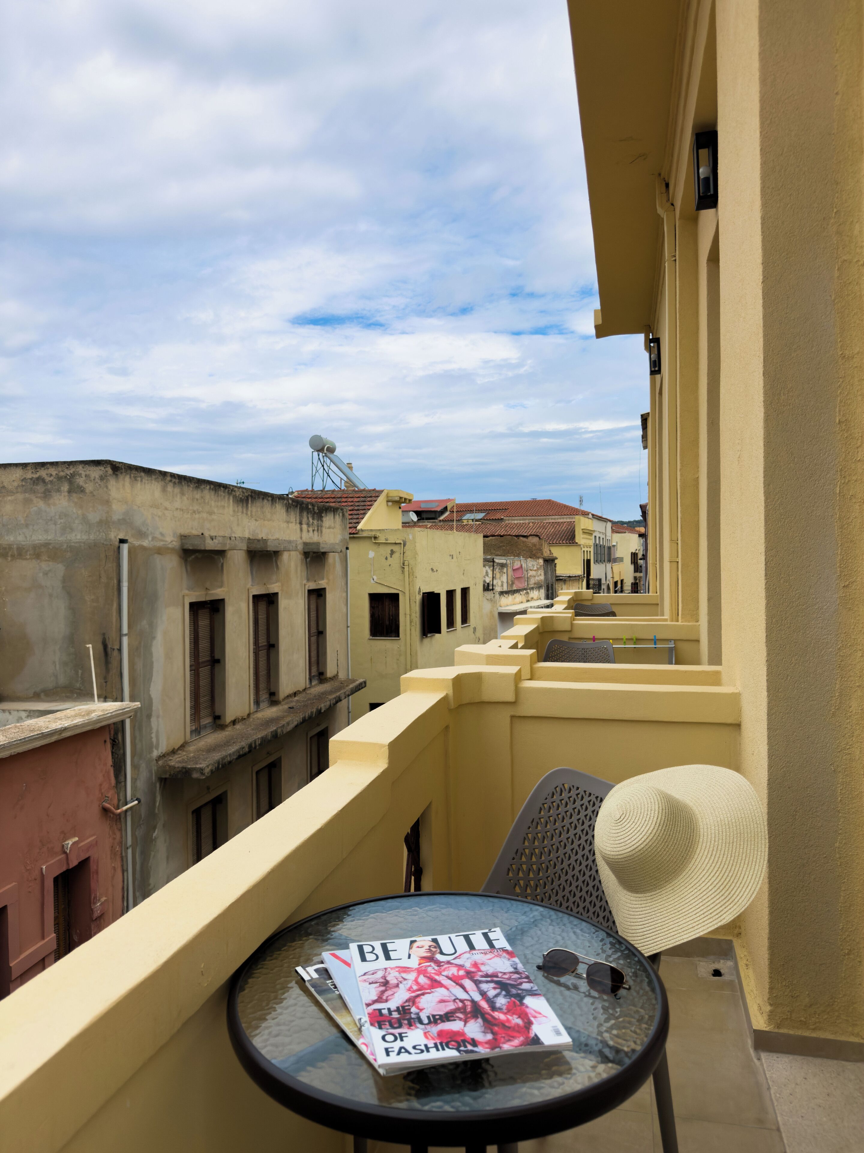 Un balcón con una revista, un sombrero y una mesa.