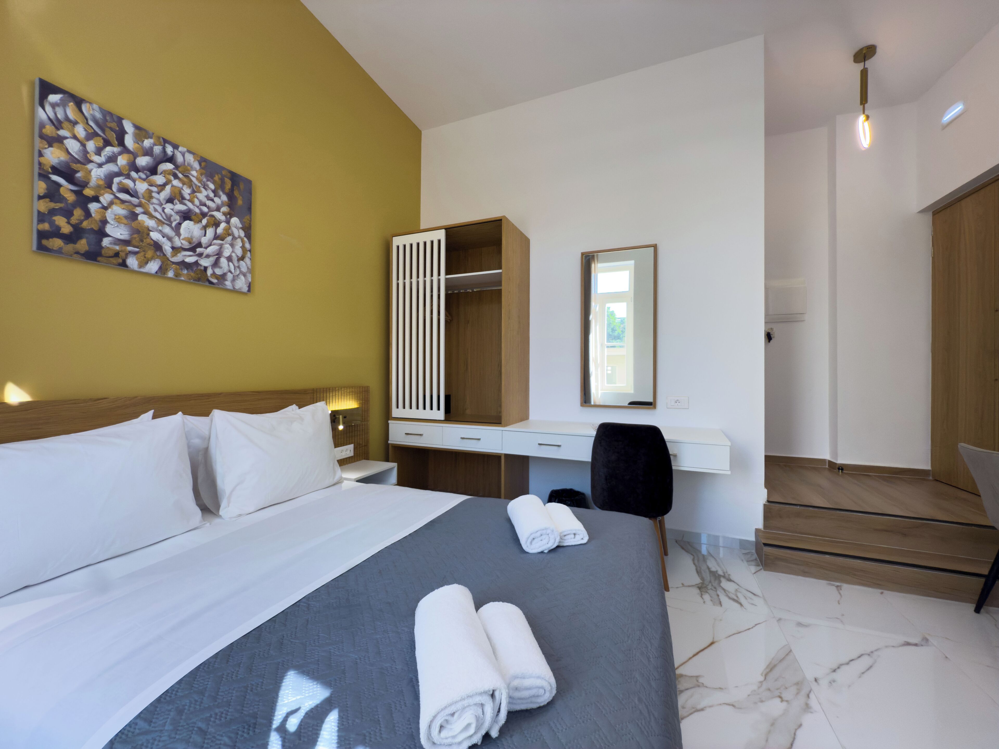 Habitación de hotel con cama, escritorio, silla, armario y un cuadro en la pared.