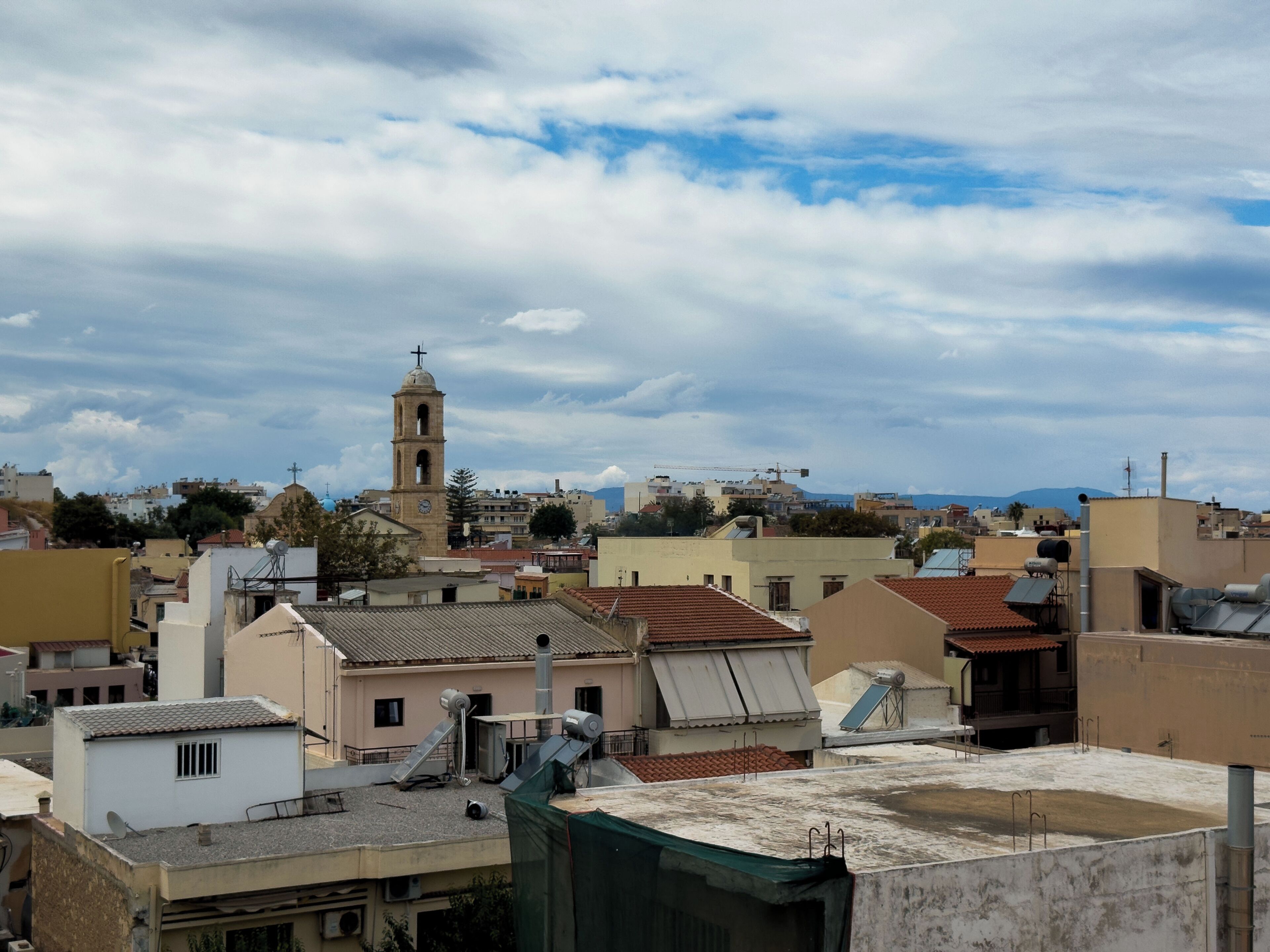 A cityscape with a prominent church tower, various residential buildings, and a clear sky.