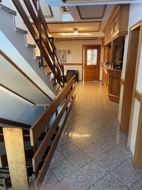 Una escalera con barandillas de madera que conduce a un rellano con piso de baldosas.