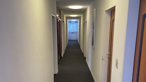 A long, narrow hallway with carpeted floors and white walls. - Gästehaus am Kurpark VS (Villingen-Schwenningen)