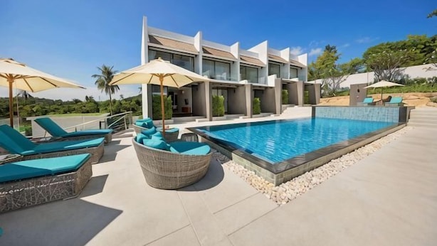 A modern hotel with a swimming pool, lounge chairs, and umbrellas. - Choeng mon Modern 2BR Villa (Koh Samui)
