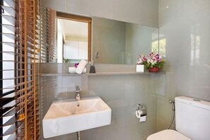 A bathroom with a white sink, a toilet, a mirror, and a window with blinds. - Choeng mon Modern 2BR Villa (Koh Samui)