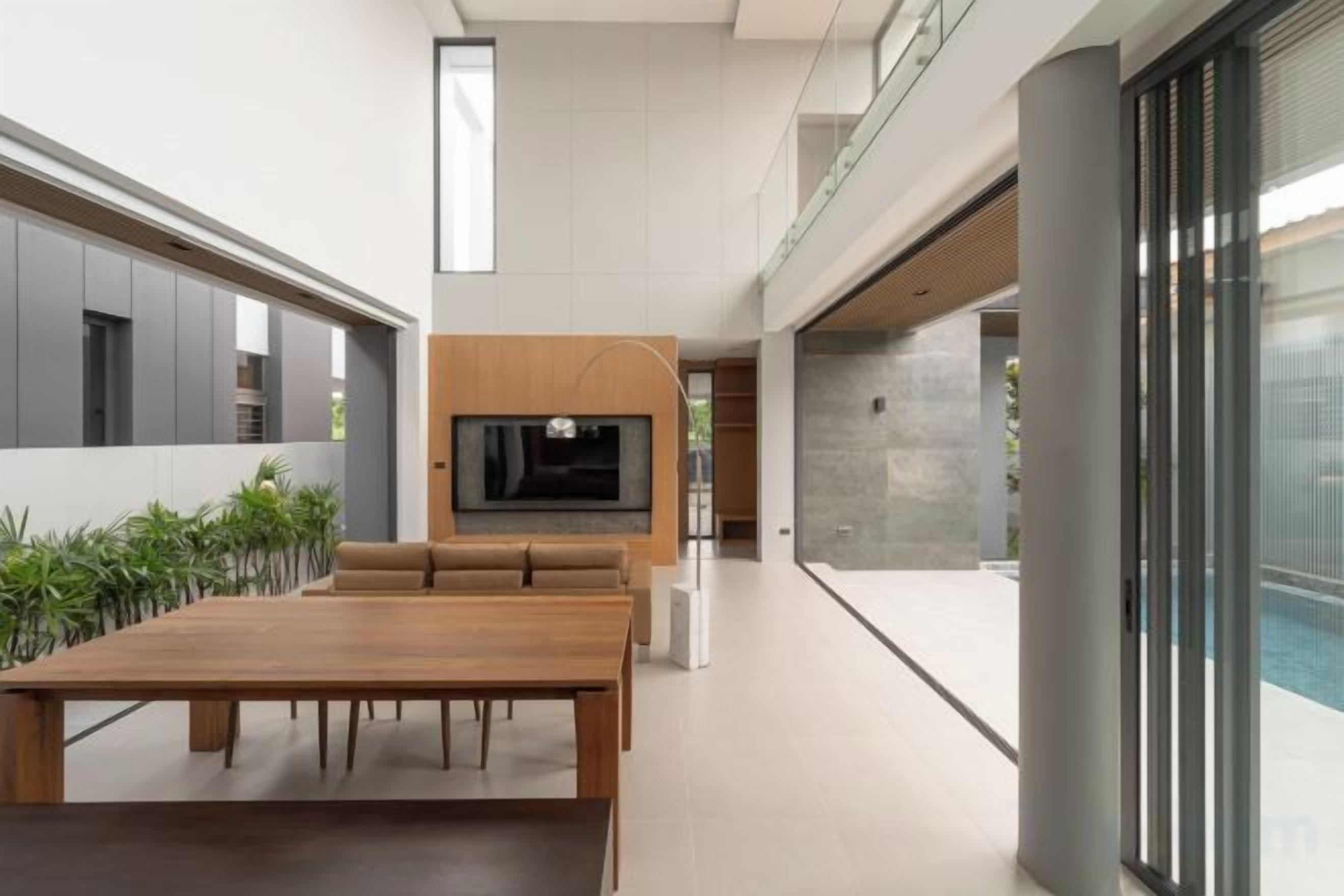 A modern interior with a dining area, a flat-screen TV mounted on a wall, and a glass door leading to a pool area.