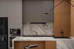 A modern kitchen with a marble countertop, wooden cabinets, and a black faucet. - Horizon J1 Villa Private Pool 3BR Near Nimman (Chiang Mai)