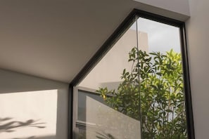 A corner of a room with a large window, a plant, and a wall. - Horizon J1 Villa Private Pool 3BR Near Nimman (Chiang Mai)