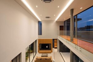 A modern interior with a sofa, a fireplace, and a glass railing overlooking a cityscape.