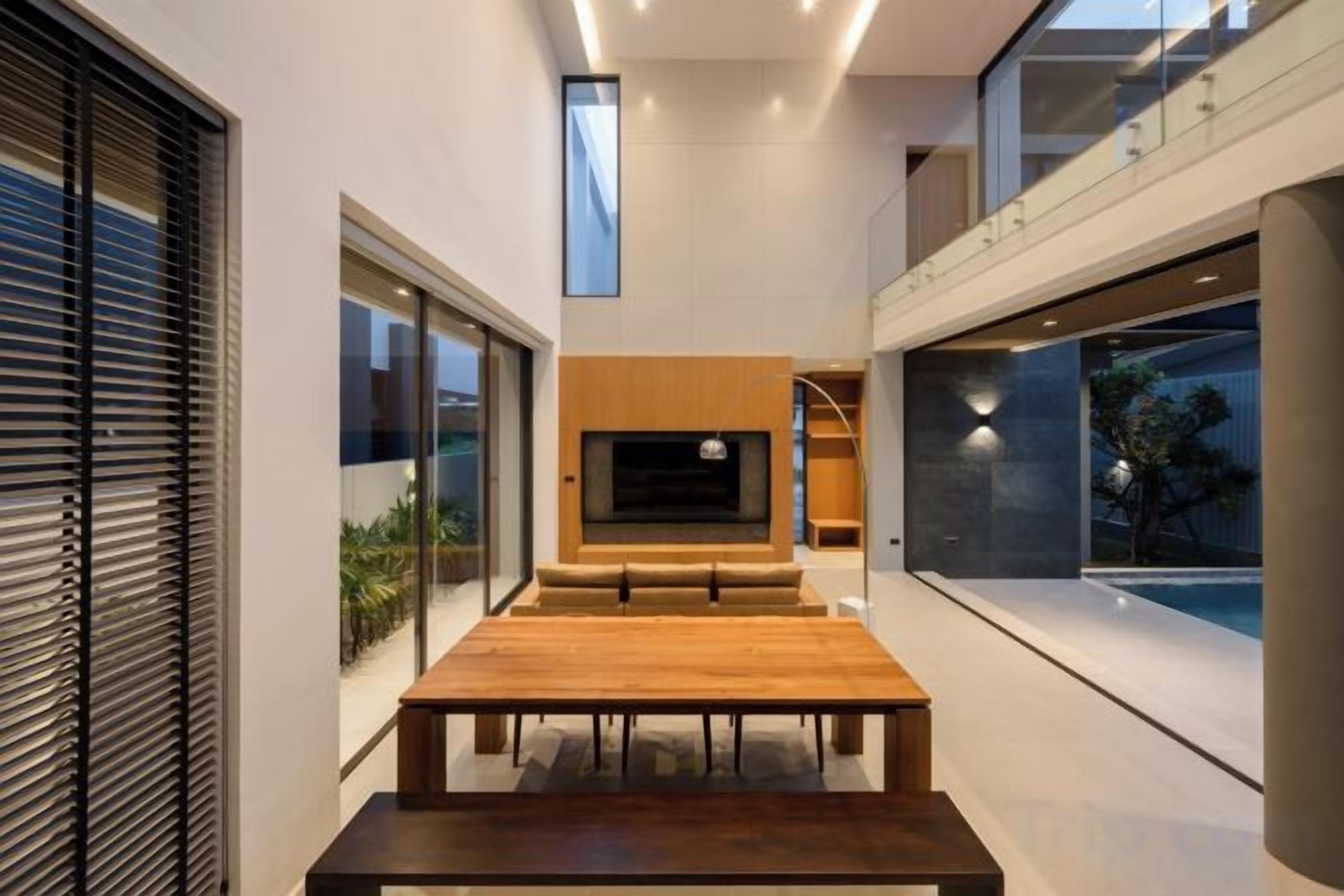 A modern interior with a wooden dining table, a flat-screen TV, and a view of the outdoors.