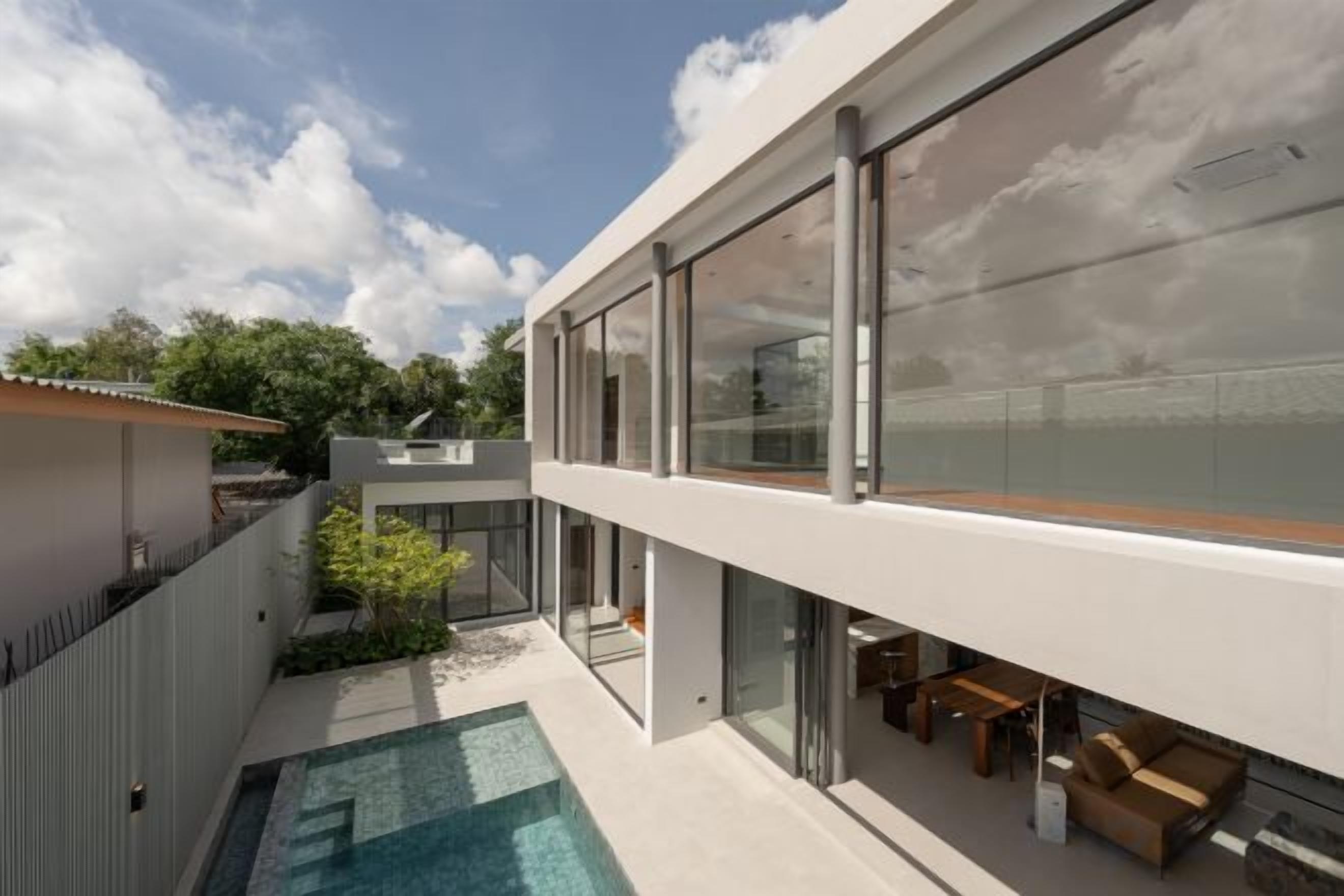 A modern building with a swimming pool, large windows, and outdoor seating.