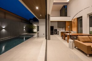 Een modern interieur met een zwembad, een eethoek en een zithoek.