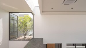 Un intérieur moderne avec une grande fenêtre, un escalier en béton et un design minimaliste.