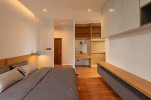 Een slaapkamer met een bed, nachtkastjes, een garderobe en inbouwkasten.