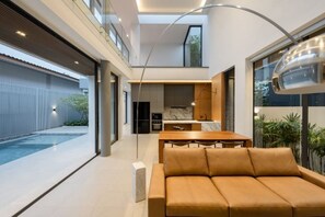 Een modern interieur met een bank, eettafel en keukenhoek.