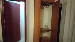 Ein Zimmer mit einem Holzschrank, einer kleinen Ablagefläche mit einem dekorativen Gegenstand und einer Tür zu einem anderen Raum.