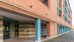 A modern building with a covered entrance, large windows, and a brick facade.