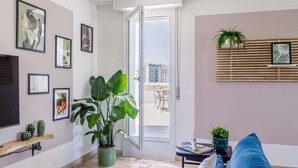 A modern living room with a large plant, a sofa, and a dining area visible through an open door. - Skyline Eighth Heaven - Affitti Brevi Italia (Modena)