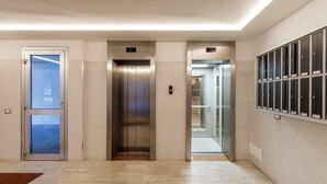 A modern elevator area with two elevators, a glass door, and a row of lockers on the right. - Skyline Eighth Heaven - Affitti Brevi Italia (Modena)