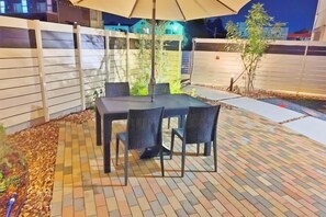 An outdoor patio with a table and chairs, surrounded by a brick floor and a fence. - Tsukuba Garden House QIAO No.361 (Tsukuba)