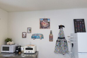 A kitchen with a microwave, toaster, and a refrigerator. There are wall decorations including a vintage car and a beer bottle. - Tsukuba Garden House QIAO No.361 (Tsukuba)