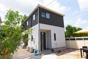 A two-story residential building with a front door, a small porch, and a covered outdoor seating area. - Tsukuba Garden House QIAO No.361 (Tsukuba)