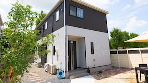 Ein modernes, zweistöckiges Haus mit dunkler Außenfassade und weißem Unterteil.