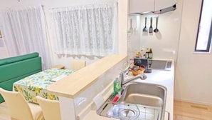Eine kleine Küche mit Spüle, einem Tisch mit Stühlen und einem grünen Sofa.