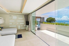 Ein modernes Zimmer mit Balkon, einer Couch, einem Fernseher und Meerblick.