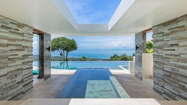 A modern interior with a view of the sea, stone walls, and a pool area. - Villa Spice Samui (Koh Samui)