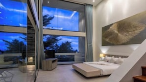 A modern bedroom with a large bed, a view through floor-to-ceiling windows, and a staircase. - Villa Spice Samui (Koh Samui)