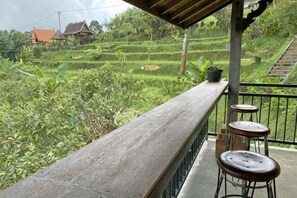 A wooden balcony with a view of terraced fields, a railing, and two stools. - Jatiluwih Guava Eco Living Managed by Manara (Bali)