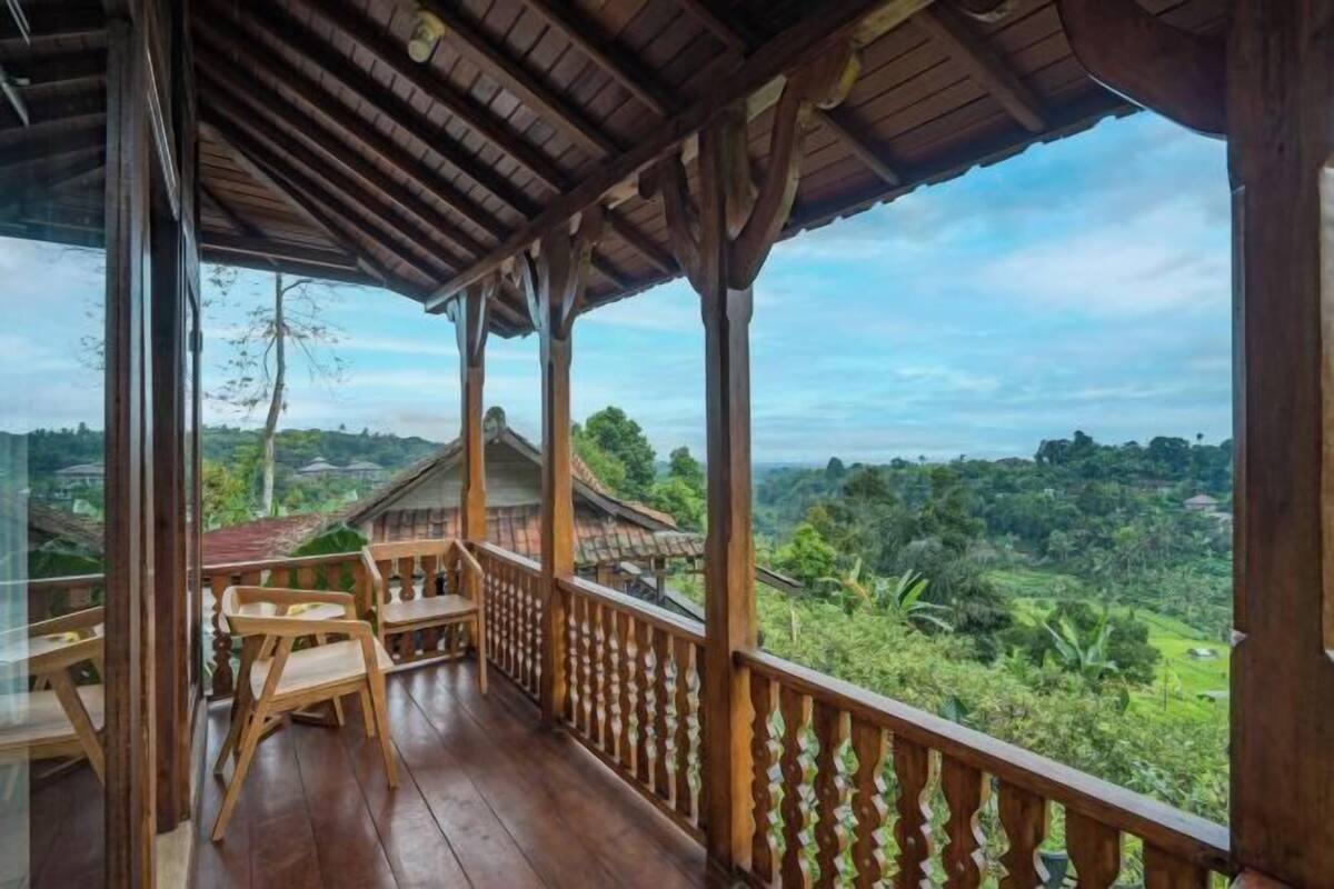 A wooden balcony with a view of a lush landscape.