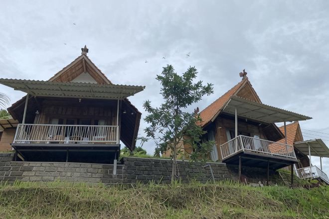 A traditional two-story house with a balcony on the ground floor and a staircase leading to the upper floor.