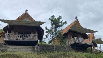 A traditional two-story house with a balcony on the ground floor and a staircase leading to the upper floor.