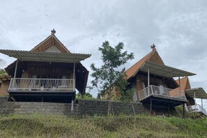 Ein traditionelles, zweistöckiges Haus mit einem Balkon im Erdgeschoss und einer Treppe zum Obergeschoss.