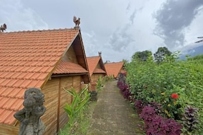 Eine Reihe von Holzhäusern mit roten Ziegeldächern und eine Steinstatue auf der linken Seite.