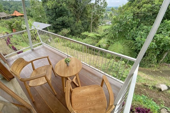 A balcony with wooden furniture and a view of lush greenery.