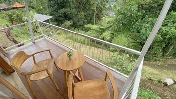 A balcony with wooden furniture and a view of lush greenery.