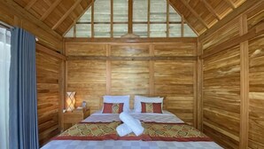Habitación con paneles de madera, una cama, una mesita de noche y un ventanal.