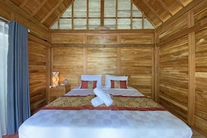Ein Zimmer mit Holzwänden, einem Bett, einem Nachttisch und einem Fenster.