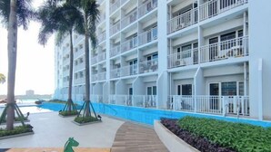 Un hotel de varios pisos con balcones, piscina y zona de juegos para niños.